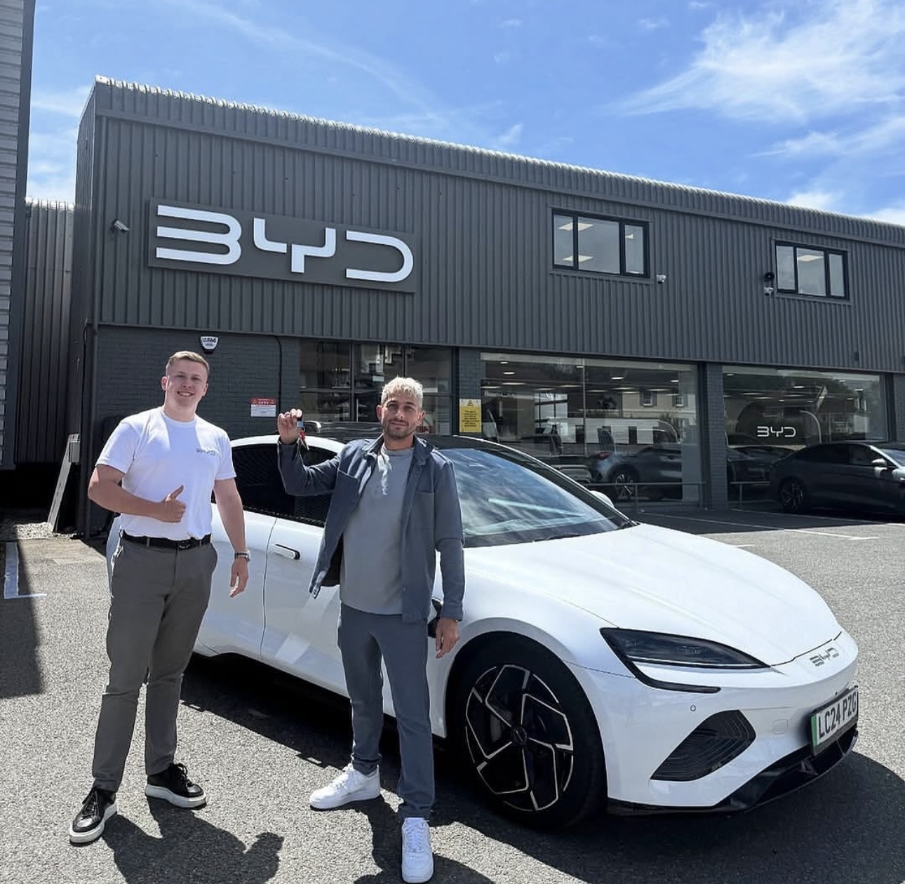 Family standing with new BYD car and red bow